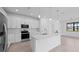 Well-lit kitchen with stainless steel appliances, a large island, white cabinetry, and modern fixtures at 17200 Luminous Ave, Venice, FL 34293