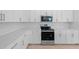 Close up of a modern kitchen featuring stainless steel appliances, white cabinets, and quartz countertops at 17200 Luminous Ave, Venice, FL 34293