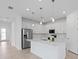 Modern kitchen with stainless steel appliances, white cabinets, quartz countertops, and an island with pendant lighting at 17200 Luminous Ave, Venice, FL 34293