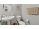 Neutral-toned half-bathroom featuring a pedestal sink, toilet, and decorative wall art at 19316 Eagle Creek Ln, Tampa, FL 33647