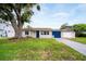 Charming single-story home featuring a well-maintained lawn, blue garage door, and inviting front porch at 250 W Canal Dr, Palm Harbor, FL 34684