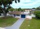 Charming single-story home with a blue garage door, a well-manicured lawn, and a white picket fence at 250 W Canal Dr, Palm Harbor, FL 34684