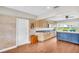 Open kitchen with tan cabinetry, granite countertops, a blue island, and hardwood flooring at 250 W Canal Dr, Palm Harbor, FL 34684