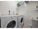 Laundry room with white walls, tile floors, washer and dryer and shelving for storage at 2622 W Horatio St, Tampa, FL 33609