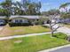 Single-story house featuring a green lawn, mature trees, and a tidy front yard, exuding a welcoming and cozy atmosphere at 3072 Keene Park Dr, Largo, FL 33771