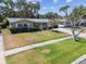 Attractive single-story home with a well-manicured lawn, mature trees, and a quaint front yard, offering a warm curb appeal at 3072 Keene Park Dr, Largo, FL 33771