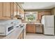 Bright kitchen with white appliances, light wood cabinets, countertops and a charming window with a bird ornament at 3072 Keene Park Dr, Largo, FL 33771