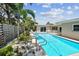 Outdoor pool surrounded by lush greenery with patio seating offers a tranquil and private oasis for relaxation and entertainment at 3072 Keene Park Dr, Largo, FL 33771