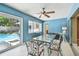 Bright sunroom with an outdoor view of a swimming pool, featuring a glass-top dining table and colorful chairs at 3072 Keene Park Dr, Largo, FL 33771