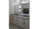Bathroom with double granite sinks, white cabinets, black hardware, and large mirror at 3125 Tucson Rd, North Port, FL 34286