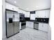 Stylish kitchen with stainless steel appliances, white cabinets, and sleek marble tile flooring at 3145 Munson St, New Port Richey, FL 34655