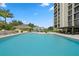 Large pool area with lounge chairs, tables, umbrellas, and a building in the background at 3301 Bayshore Blvd # 2207B, Tampa, FL 33629
