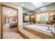 Luxurious bathroom with mirrored walls, soaking tub, and tiled steps leading into the space at 3427 Forest Bridge Cir, Brandon, FL 33511