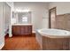 Bright bathroom features a soaking tub, tiled shower, and double vanity with wood cabinets and tile floors at 3610 Montero Ct, Sun City Center, FL 33573