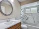 Bright bathroom features a modern vanity, round mirror and a marble-tiled shower and tub combination at 3810 Hollister Pl, Brandon, FL 33511