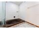 Dated bathroom features a unique dark tub, white tiled walls, and shower head at 4104 W Watrous Ave, Tampa, FL 33629