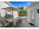 Outdoor dining area with a gray table, chairs, umbrella, and cafe string lights on a stone paver patio at 4935 W Bay Way Pl, Tampa, FL 33629