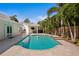 Backyard pool surrounded by stone pavers, tropical landscaping, and an outdoor entertainment area with a tv and grill at 4935 W Bay Way Pl, Tampa, FL 33629