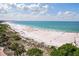 Wide sandy beach with clear blue ocean, beachgoers, and sunny skies at 506 71St Ave # 7, St Pete Beach, FL 33706