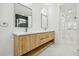 Elegant bathroom featuring dual sinks, light wood cabinets, marble countertops, and modern fixtures at 5406 N Pershing Pl, Tampa, FL 33603
