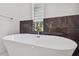 Luxurious bathroom featuring a freestanding tub, dark tile accent wall, and a window with natural light at 5406 N Pershing Pl, Tampa, FL 33603