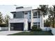 Contemporary home featuring a modern facade, sleek garage door, and manicured lawn at 5406 N Pershing Pl, Tampa, FL 33603
