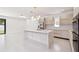 Spacious open-concept kitchen featuring an island with bar, stainless steel refrigerator, and modern cabinetry at 5406 N Pershing Pl, Tampa, FL 33603