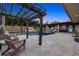 A luxurious outdoor living space featuring a pergola, travertine flooring, a fireplace, a pool and a covered kitchen and living area at 6129 Leeland S St, St Petersburg, FL 33715