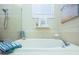 Close up of a soaking tub with tile surround, handheld shower, and beach-themed decor at 6303 Vista Verde E Dr, Gulfport, FL 33707