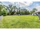 Large backyard with lush green grass, mature trees, and play structures for outdoor enjoyment at 6702 Towhe Dr, Seffner, FL 33584