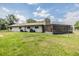 Wide shot of the home's backyard featuring green grass, a stone chimney, and an enclosed patio at 6702 Towhe Dr, Seffner, FL 33584