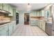 Charming kitchen featuring light green cabinets, a tiled backsplash, and stainless steel double ovens at 6702 Towhe Dr, Seffner, FL 33584