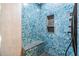 Luxurious shower featuring eye-catching blue mosaic tiles and convenient built-in shelving at 6702 Towhe Dr, Seffner, FL 33584