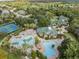 Aerial view of a community pool, tennis courts, clubhouse, and lush greenery in a residential neighborhood at 7815 Blue Spring Dr, Land O Lakes, FL 34637