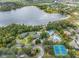 Aerial view of community clubhouse featuring tennis courts, pool, and surrounding trees near the lake at 7815 Blue Spring Dr, Land O Lakes, FL 34637