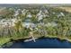 Aerial view of a lakeside community featuring a dock, swimming pool, tennis court, and lush landscaping at 7815 Blue Spring Dr, Land O Lakes, FL 34637