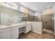 Bright bathroom featuring double sinks, a large mirror, and a glass-enclosed walk-in shower with grab bars at 7815 Blue Spring Dr, Land O Lakes, FL 34637