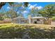 Expansive backyard featuring a screened-in pool and spa, lush landscaping, and privacy fence at 914 Woodland Dr, Palm Harbor, FL 34683
