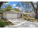 Single-story home with a well-manicured lawn, mature trees, and a large two car garage at 914 Woodland Dr, Palm Harbor, FL 34683