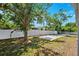 A spacious backyard with a white fence, concrete pad and mature trees provides ample space for activities at 10115 Kenlake Dr, Riverview, FL 33578
