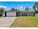 Single-story home with a two-car garage, well-kept lawn, and mature trees at 10115 Kenlake Dr, Riverview, FL 33578