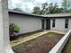 Exterior facade showcasing a front patio with mulch and small plants along the walls of the building with a door and sliding glass door at 1309 Malone Ave, Spring Hill, FL 34606