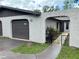 Gray home facade featuring an arched entryway leading to the front door with a storm door, gray walls, and manicured landscaping at 1309 Malone Ave, Spring Hill, FL 34606
