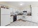 Clean kitchen features white cabinets, a black dishwasher, and white tile flooring at 1309 Malone Ave, Spring Hill, FL 34606