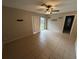 Neutral-toned living room featuring tile floors, a ceiling fan with lighting, a sliding glass door, and a view of the backyard at 1309 Malone Ave, Spring Hill, FL 34606