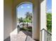 This outdoor view is from a balcony with brick flooring overlooking green shrubbery and palm trees at 1341 Marinella Dr, Palm Harbor, FL 34683