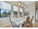Bright dining room with glass table and seating for six set in front of three large windows at 1341 Marinella Dr, Palm Harbor, FL 34683