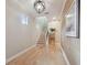 Inviting hallway features hardwood floors, an elegant light fixture, and staircase access to upper level at 1341 Marinella Dr, Palm Harbor, FL 34683