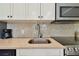 Close up of the neutral tile backsplash and stainless steel sink and appliances at 1341 Marinella Dr, Palm Harbor, FL 34683