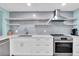Contemporary kitchen with stainless steel appliances, white cabinets, and open shelving at 15400 Gulf Blvd # 202, Madeira Beach, FL 33708